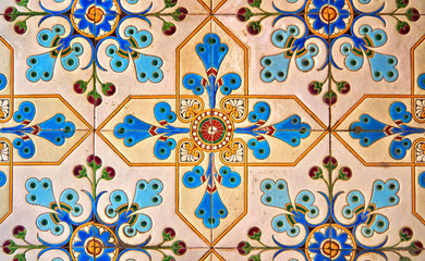 Ceramic tiles with colorful floral and geometric patterns for wall and floor decoration. Old concrete block surface background.
