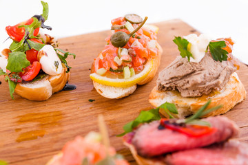 Assorted bruschett on a wooden board on a white background