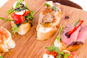 Assorted bruschett on a wooden board on a white background