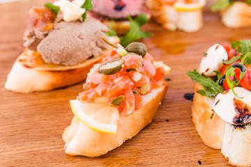 Assorted bruschett on a wooden board on a white background