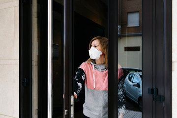 Fototapeta na wymiar A woman goes outside from her house with a face mask