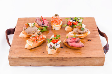 Assorted bruschett on a wooden board on a white background