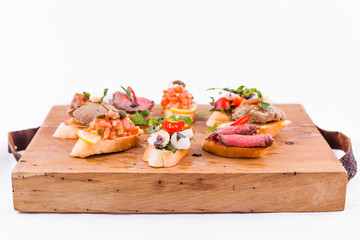 Assorted bruschett on a wooden board on a white background