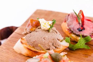 Assorted bruschett on a wooden board on a white background