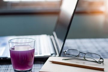 Close Up a glass of water containing medication or supplements, Morning time with notebook computer and work equipment, Normal practice by working at home during covid-19 outbreak around the world.