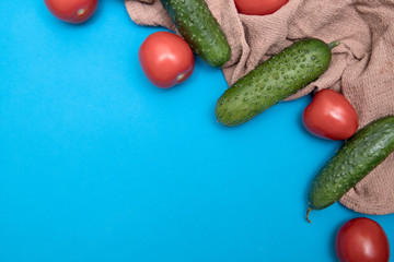 Vegetables on a blue background. Cucumbers and tomatoes on a beige waffle towel. Empty space. Place for the recipe. Place for the menu. Home cosmetology. Cooking training online. Seasonal food.