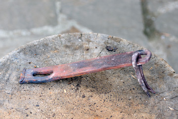 Fused metal bolt with a bracket on a wooden block close up