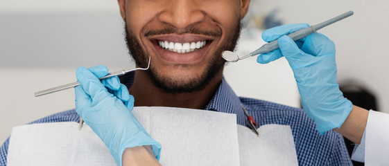 Cropped of dentist hands with tools and smiling patient