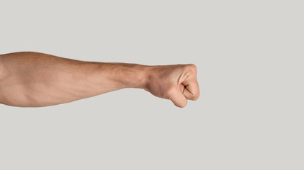 Millennial man clenching fist on light grey background, close up. Copy space. Panorama