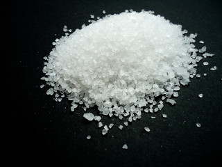 Natural sea salt grains on black background, pile of salt crystal
