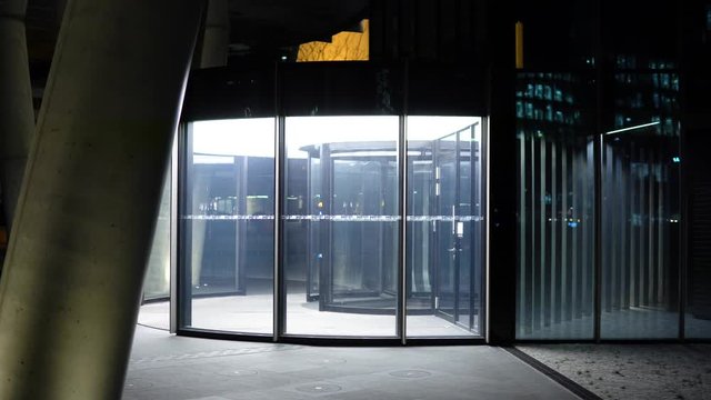 A revolving door to a building in an urban area at night - side view