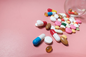 Colorful pills and capsule on pink background 
