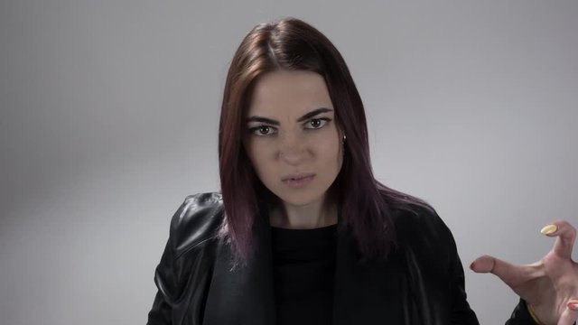 Young woman with coloured hair moves hands and yells with hate and anger. Portrait of the girl showing emotion of rage in slow motion. Theme of revealing different feelings.