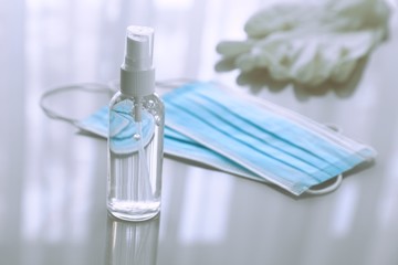 Disposable medical masks, hand sanitizer and latex gloves on light gray background