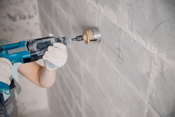 Builder worker pneumatic hammer drills hole in concrete brick wall with diamond crown for electric cable, socket, switch