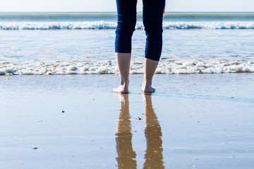 woman in jeans and barefoot walking on the shore of the beach. healthy and relax