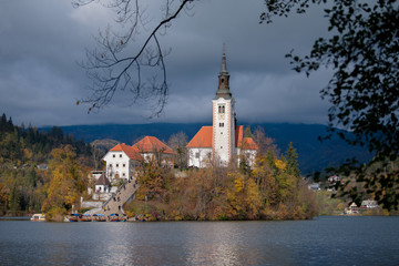 Santa Maria Church catholic church situated on an island on Bled lake with Alps mountains on the background. Autumn nature landscape.