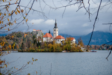 Panoramic view of Santa Maria Church on the alpine Bled Lake (Blejsko jezero) in autumn , Slovenia. Scenic view of the lake, island with church, Bled castle, mountains and blue sky with clouds