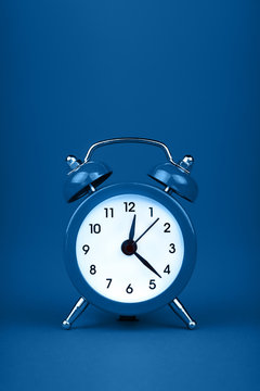 Close up one classic alarm clock over blue background