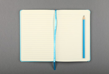 Open blue notebook with pencil over grey