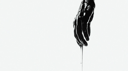 hand in black liquid on a white background
