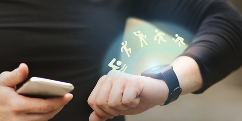 Young man looking at smart watch exercising outside