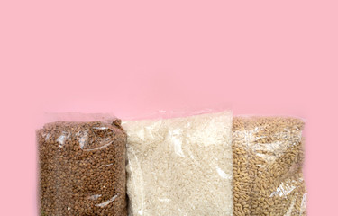 three bags with groats on a pink background