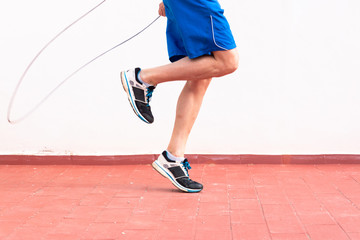 Legs of a man working out with a skipping rope on the terrace of his house