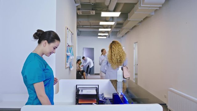 Happy and smiling large nurse at the reception meeting the patient answer on the phone and greeting other medical stuff