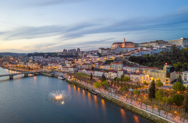Fototapeta na wymiar Coimbra drone aerial city view at sunset with colorful fountain in Mondego river and beautiful historic buildings, in Portugal