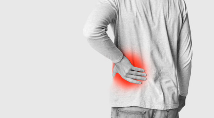 Man holding his back, monochrome photo with red, as symbol of inflammation