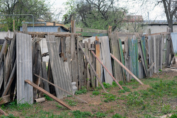 Old fence made of boards and pieces of slate. Fencing the site with different materials. The fence...
