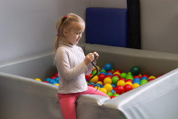 little girl plays in the room of sensory integration in the pool with balls different colors