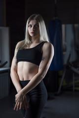 Fototapeta na wymiar Portrait of a young girl, a fitness trainer in a dark sports uniform with a gym.