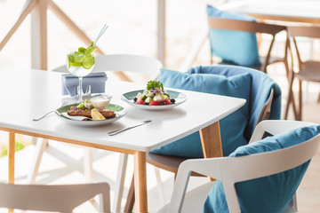 summer composition on the summer playground table and chairs . tasty meats of meat and lettuce are on the table. summer cooling cocktail. Blue pillows