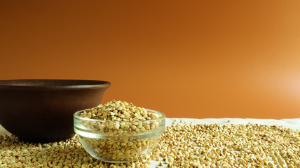 Green buckwheat in a glass transparent bowl on a brown background. healthy groats. Organic raw non-fried vegetarian food. The concept of a healthy and balanced diet. Diet Food. Copy Space