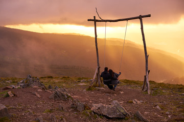 Romantic couple swinging on a Swing baloico in Lousa mountain, Portugal at sunset