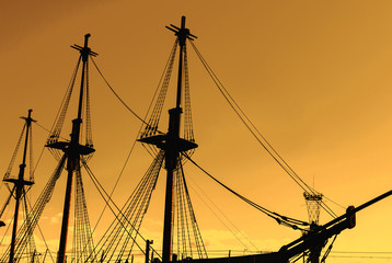 Silhouette of an old, ancient, wooden ship with masts on a sunset background