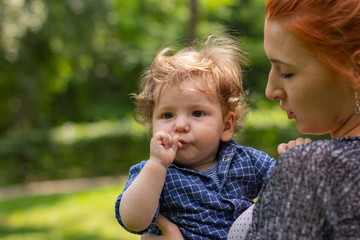Fototapeta na wymiar Young red-haired woman with a child. Mom with her son outdoor. Happy family. Young mother. Cute child.
