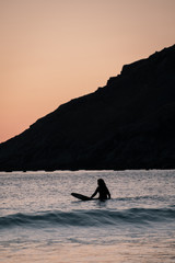 Fototapeta premium Blurred surfer on longboard. small waves during beautiful sunset. surfing behind arctic circle has advantage of midnight sun. Unstad is a famous beach in Lofoten Islands