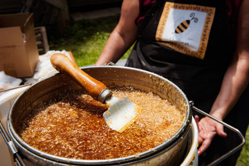 Natural raw honey being processed through a strainer to filter our bees wax.