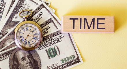 Wooden block with a TAX TIME text and coin stack with clock for Tax Concept