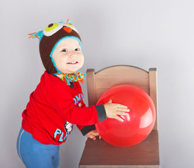 Little boy is playing with red ballon. 