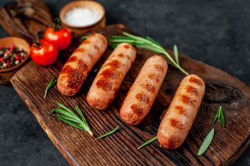classic grilled sausages with spices on a cutting board on a stone background