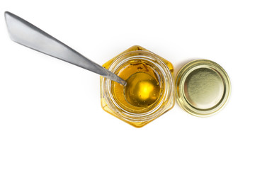 Tea spoon in a hexagonal honey jar isolated on white. Top view.