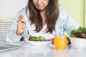 Eating healthy breakfast concept. woman holding dish of salad with variety vegetables and glass of orange juice on the floor in the morning at home.