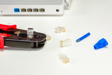 Crimping tool, internet Wi-Fi router, RJ45 connectors, blue boot for rj-45 plug for home Internet connection. Home network concept, close up.