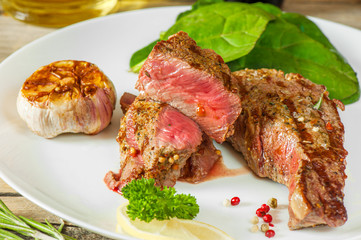 medium beef steak with blood and vegetables on a white plate