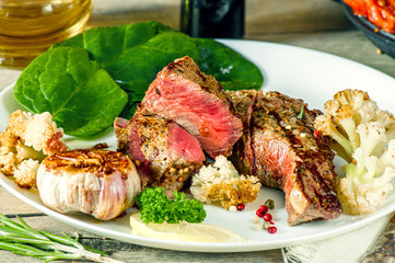 medium beef steak with blood and vegetables on a white plate
