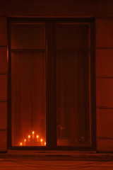 Wooden candlestick with seven electric burning candles in a window of a house